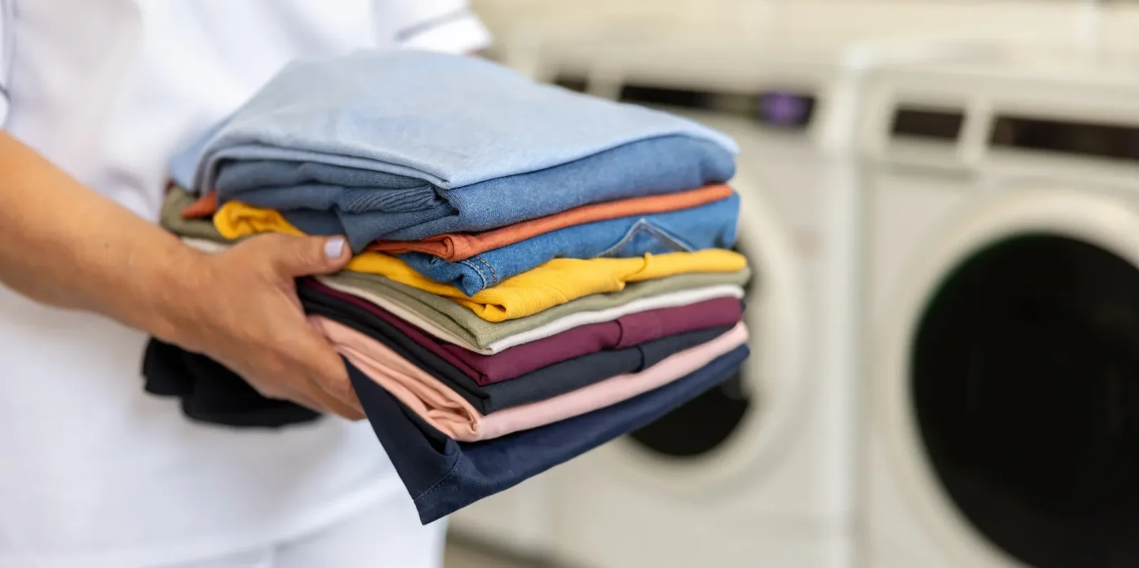 Freshly folded laundry being carried past a washing machine