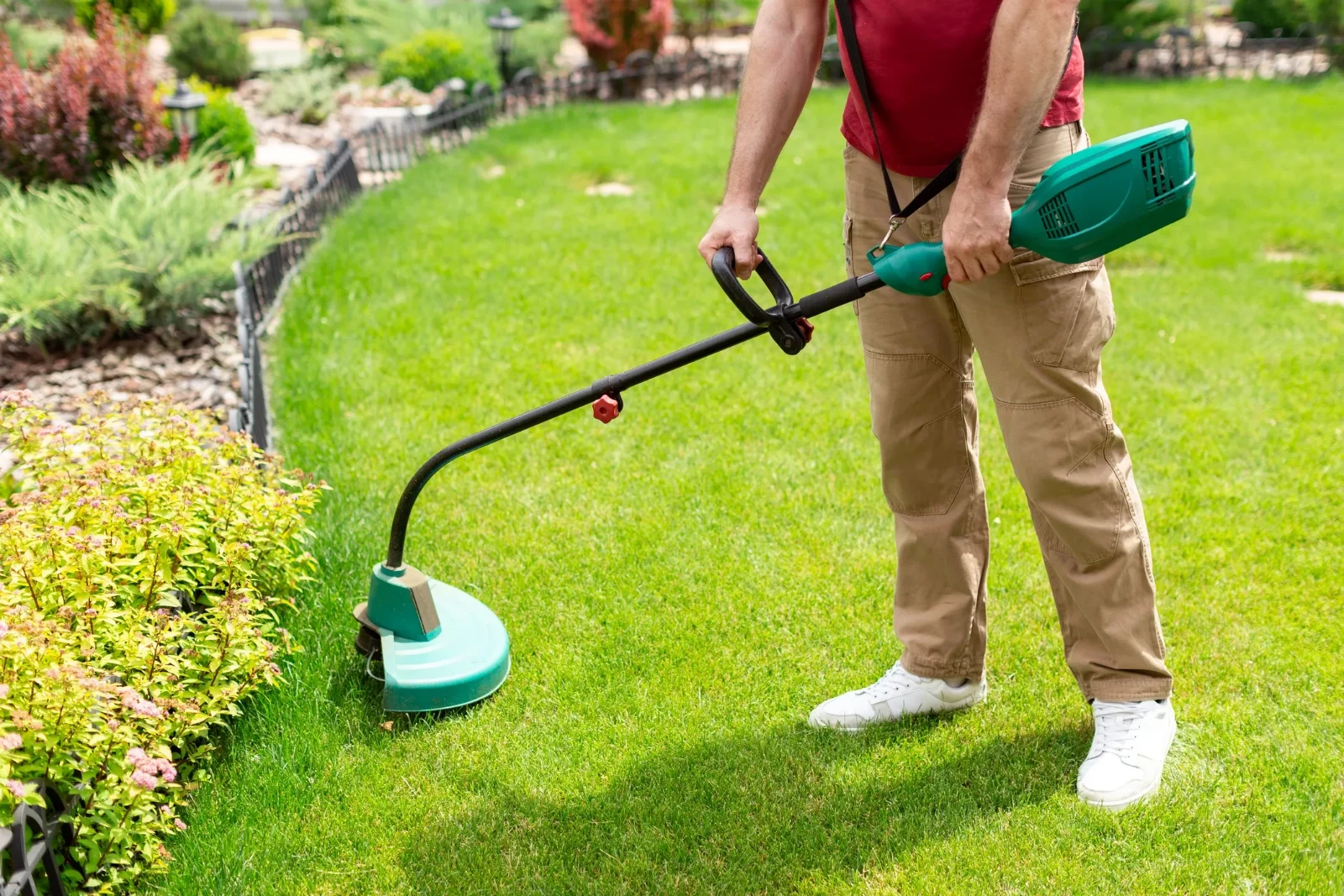 A support worker trimming a garden lawn
